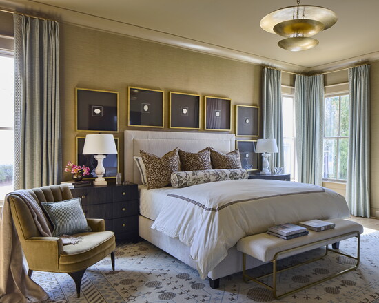 Grasscloth wallcovering and black case pieces set the tone in the primary suite. Marble lamps and a 36-inch tiered brass chandelier from Currey & Company add po