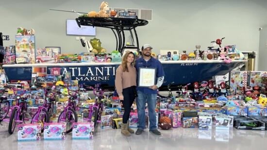 Kristen and husband Brad stand infront of "Stuff the Boat" for Toys for Tots.