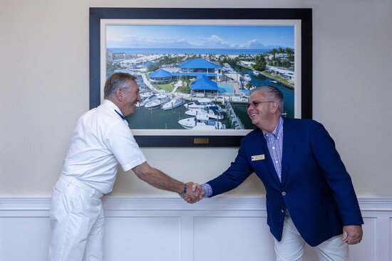 VYC General Manager and COO Ed Tindall and Commodore Michael Marquette shake hands in front of the new painting.