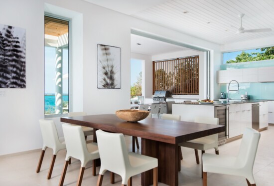 The villa’s open, airy interior design features an expansive living area lined by sliding glass doors, an open-layout kitchen, and an inviting dining area.