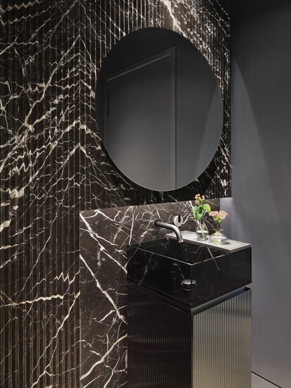 Dark colors are in for powder rooms these days, reflected by this design by Leah Bolger.