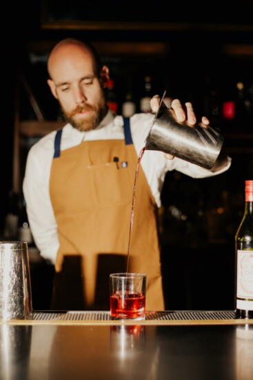 A mixologist prepares a cocktail for a customer.