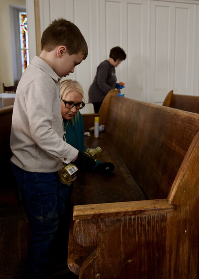 Shannon Seymore and her son Charlie, 6, polish the water damaged pews on MLK Day. In the background is Kathy Cavaleri of Parkville.