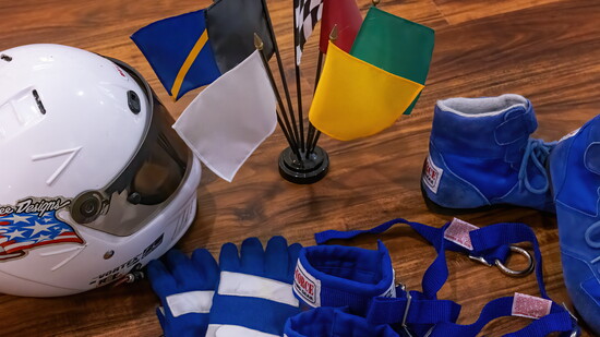 Some of Barry Burke's racing gear: helmet, gloves, arm restraints + boots. The flags represent the communication system with race drivers.