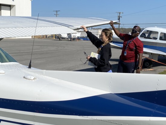 Certified Flight Instructor Jarret Jenkins (R) inspects an aircraft with a student