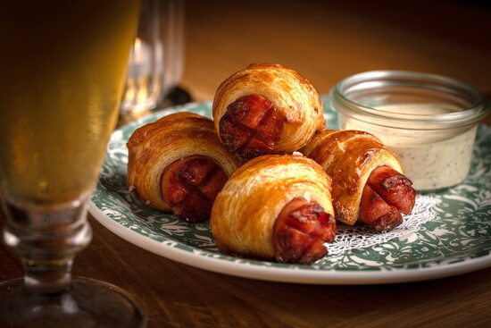 Bacon-wrapped, cheddar-stuffed dates glazed with maple create a smoky-sweet bite that’s both playful and indulgent. (Photo credit Ballyhoo Hospitality)