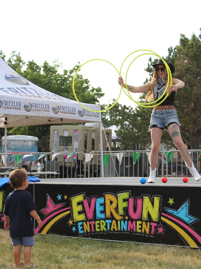 A young fan heads front and center to catch an EverFun Entertainment hula hooper on stage.