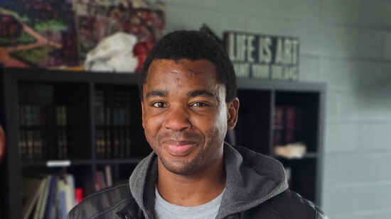 Firehouse Shelter guest, Lee, holds a t-shirt designed by 1920 Club member, Destiny, that he screen printed by hand.