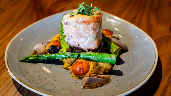 Experience the Scottish Salmon Mignon, featuring a light horseradish crust, asparagus, tomatoes, sweet potatoes, squash, and pole beans.