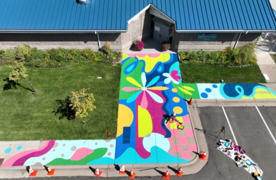 Muralist Chelsea Hart creates a mural on the sidewalk outside of Chimney Park Pool.