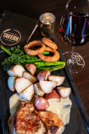 Windsor Pork Chop at the Tavern, a 15 oz. Colorado Custom Meats Co. bone-in loin with Dijon cream, roasted red potatoes, seasonal vegetables, and crispy onions.