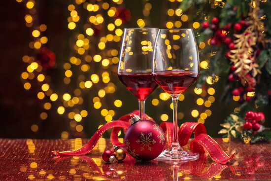 Red wine in glasses surrounded by holiday decor.