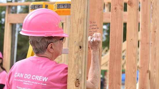 Cynthia Jansen signs a framed wall during the Can Do Crew build, marking the structure with a personal note of faith and encouragement.