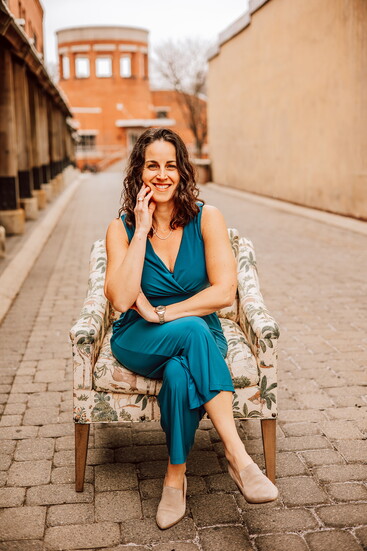 Sarah sits in a cozy Dream House armchair staged in the heart of downtown. 