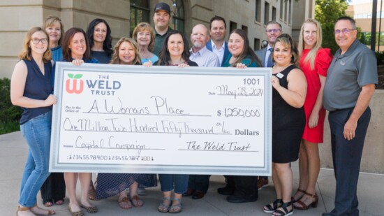 Staff from The Weld Trust and Weld Legacy Foundation present a check to A Woman’s Place Executive Director and their Board of Directors