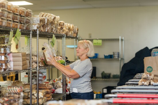 A volunteer places bread on a shelf.