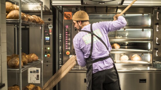Kevin Masse takes one of his fresh-baked bread out of the oven